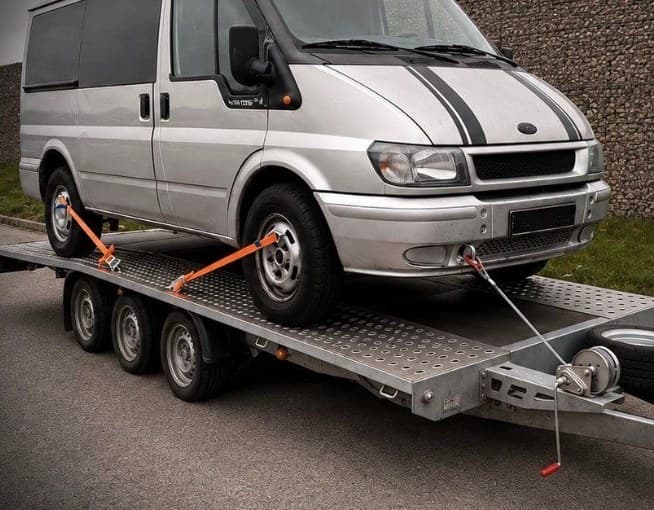 Silberner Ford Transit auf dem Transportanhänger bei einer Fahrzeug-Überführung