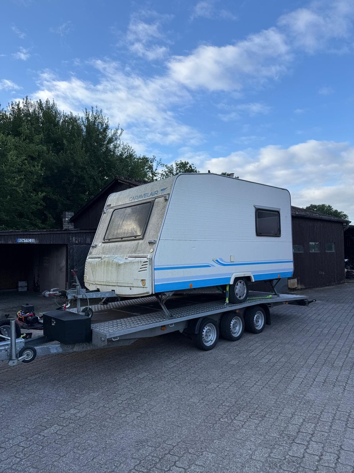 Wohnwagen gesichert auf dem dreiachsigen Transportanhänger von Car & Bike Service Blome