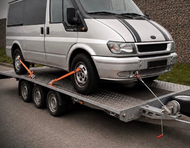 Silberner Ford Transit auf dem Transportanhänger bei einer Fahrzeug-Überführung